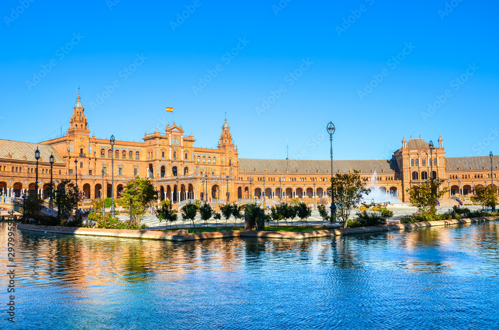 Amazing Plaza de Espana in Seville, Spain. Water reflection of the palace buildings on the adjacent canal. One of major Spanish tourist attractions. Regionalism architecture. Sevilla, Andalusia