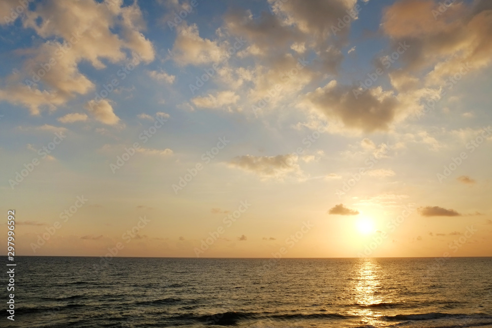 Beautiful seascape of sun setting over calm water with wind patterns and clear blue orange gradient sky without clouds. Ocean view with horizon, background with a lot of copy space for text. Beautiful seascape of sun setting over calm water with wind patterns and clear blue orange gradient sky without clouds. Ocean view with horizon, background with a lot of copy space for text.