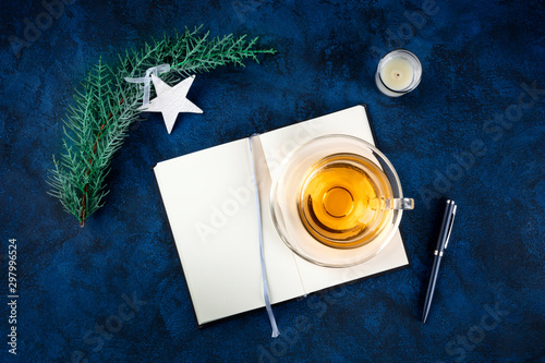 New Year resolutions, flatlay shot from above with copy space, on a dark blue background with Christmas decorations and a cup of tea