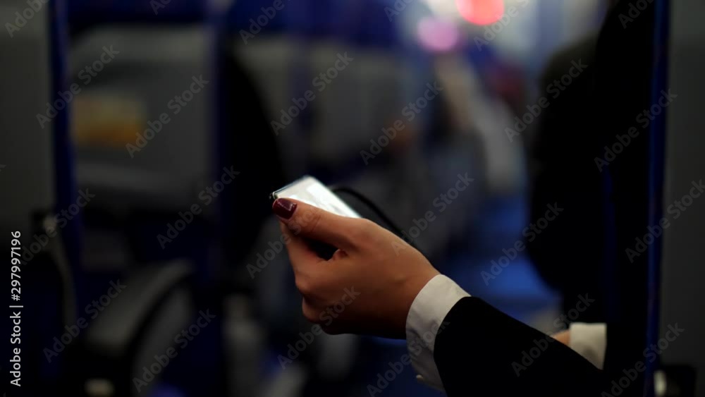 Woman watch movie using phone during flight, lean to aisle of airliner. Camera show passenger face then pan down to mobile device and back up, blurred background. Economy class cabin of Asian airline Woman watch movie using phone during flight, lean to aisle of airliner. Camera show passenger face then pan down to mobile device and back up, blurred background. Economy class cabin of Asian airline