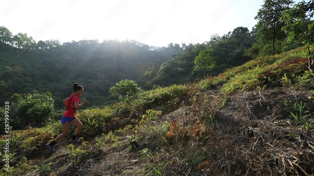 Woman ultramarathon runner running up on mountain slope in tropical forest Woman ultramarathon runner running up on mountain slope in tropical forest
