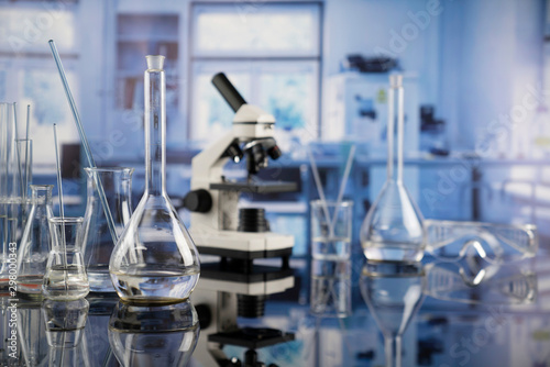 Modern scientific laboratory interior. Laboratory glassware and microscope on the glass table.