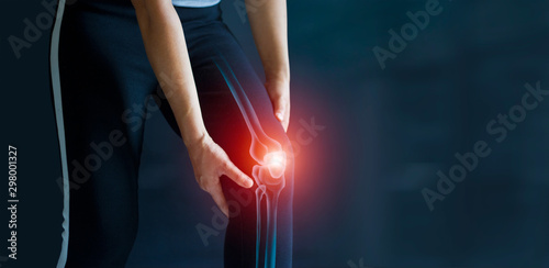 Sport woman suffering from pain in knee. Tendon problems and Joint inflammation on dark background. Healthcare and medical. photo