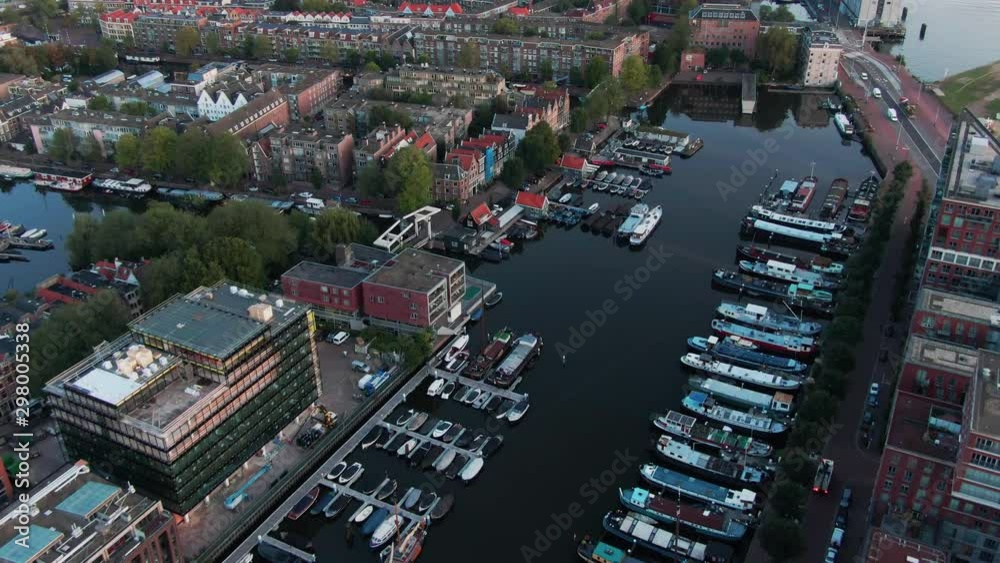 Aerial of a beautiful canal in the Westdock of Amsterdam, Netherlands with many boats on the clear water Aerial of a beautiful canal in the Westdock of Amsterdam, Netherlands with many boats on the clear water