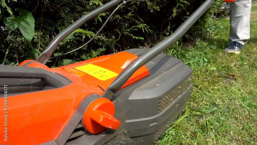 Slow motion close POV shot of someone pushing a modern, lightweight, cordless (battery operated) over tall nettles. Slow motion close POV shot of someone pushing a modern, lightweight, cordless (battery operated) over tall nettles.