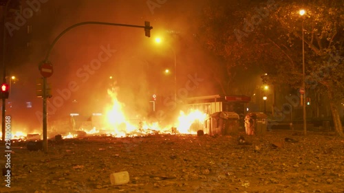 Fire from a protest riot burns in the street, while tear gas guns and emergency sirens are heard in the distance amid protest in Barcelona, Spain in October 2019. ProRes file, shot in 4K UHD.