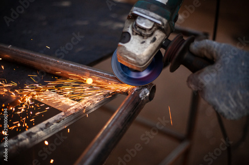 Cutting and grinding metal in the workshop. Work with a metal profile. Sparks from the work of a grinder for metal.