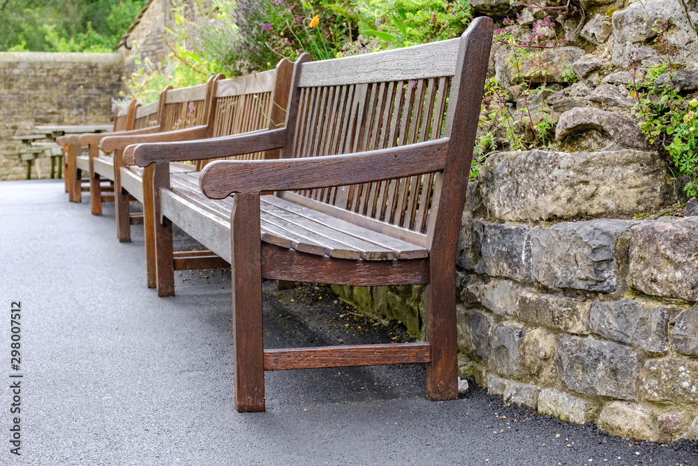 Abstract view of empty park benches seen after a rain shower. The well maintained garden area can be seen in the background.