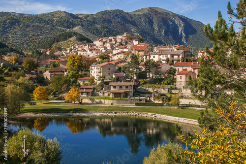 Autumn in Abruzzo: panoramic view of Villalago medieval village with blue lake and foliage photo