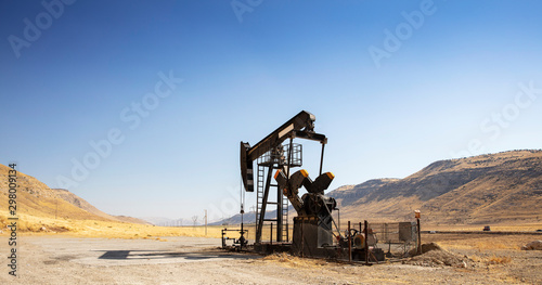 Oil drilling derricks at desert oilfield. Crude oil production from the ground. Oilfield services contractor. Oil drill rig and pump jack. Petroleum production, natural gas, liquids, NGL, additive.