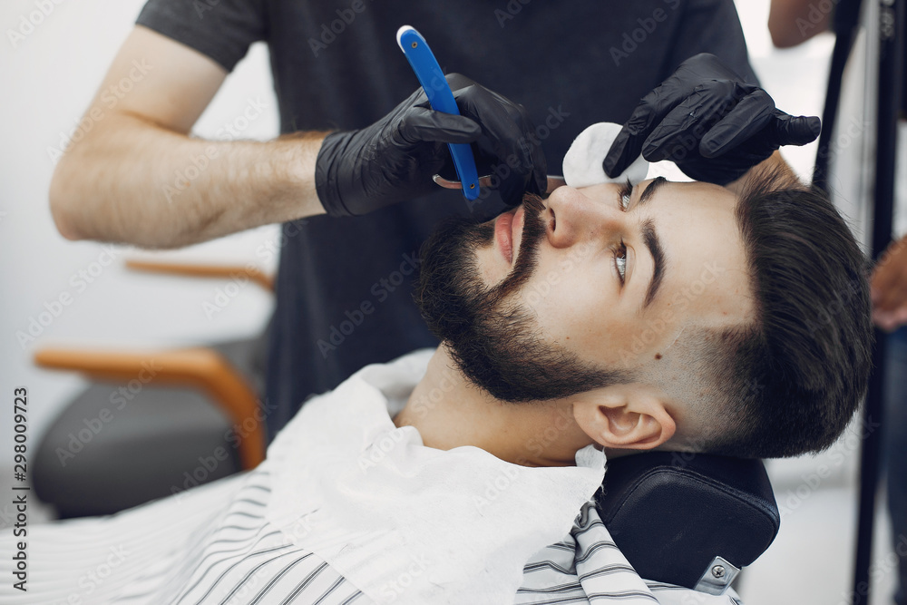 Fototapeta premium Man with a beard. Hairdresser with a client. Brunette in a barbershop