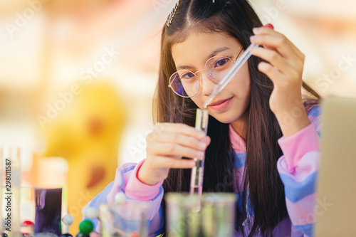 Asian teenage girl in elementary science class doing chemical experiment test try to drop color water to test tubes. Education concept