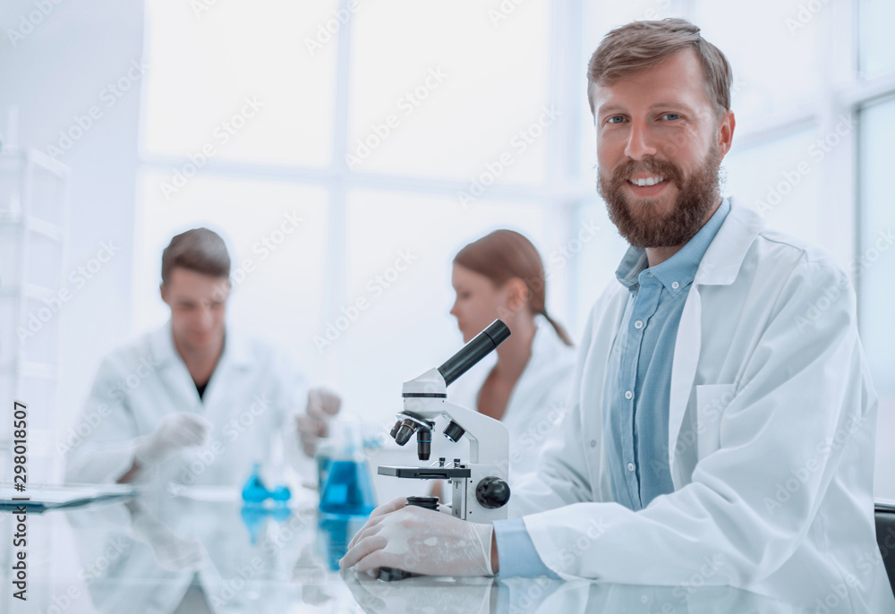 successful young scientist sitting at his Desk in the laboratory successful young scientist sitting at his Desk in the laboratory