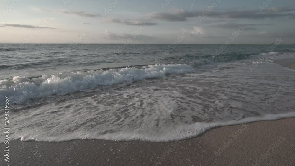 Slow Motion clip of little waves smoothly crashing on the shore of a nice beach of the mediterranean sea with soft sunrise light Slow Motion clip of little waves smoothly crashing on the shore of a nice beach of the mediterranean sea with soft sunrise light
