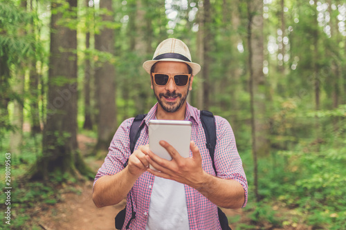 Modern hipster guy holding tablet device in nature. Travel, technology and healthy lifestyle concept.