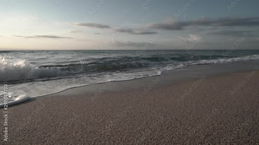 Slow Motion clip of little waves smoothly crashing on the shore of a nice beach of the mediterranean sea with soft sunrise light Slow Motion clip of little waves smoothly crashing on the shore of a nice beach of the mediterranean sea with soft sunrise light
