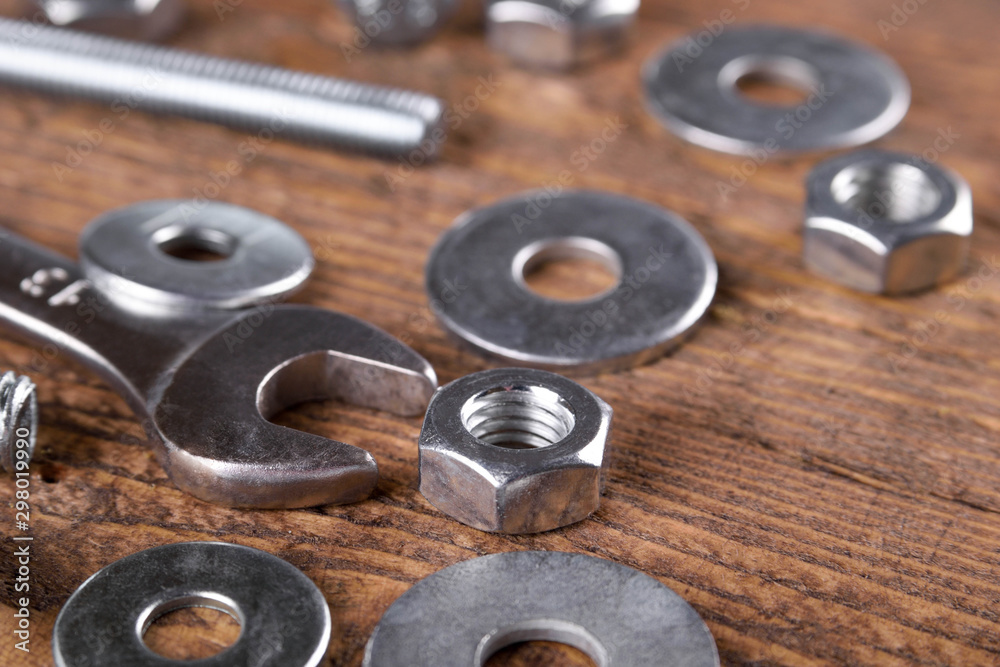 Keys wrenches, bolts, nuts, washers on a wooden background Keys wrenches, bolts, nuts, washers on a wooden background