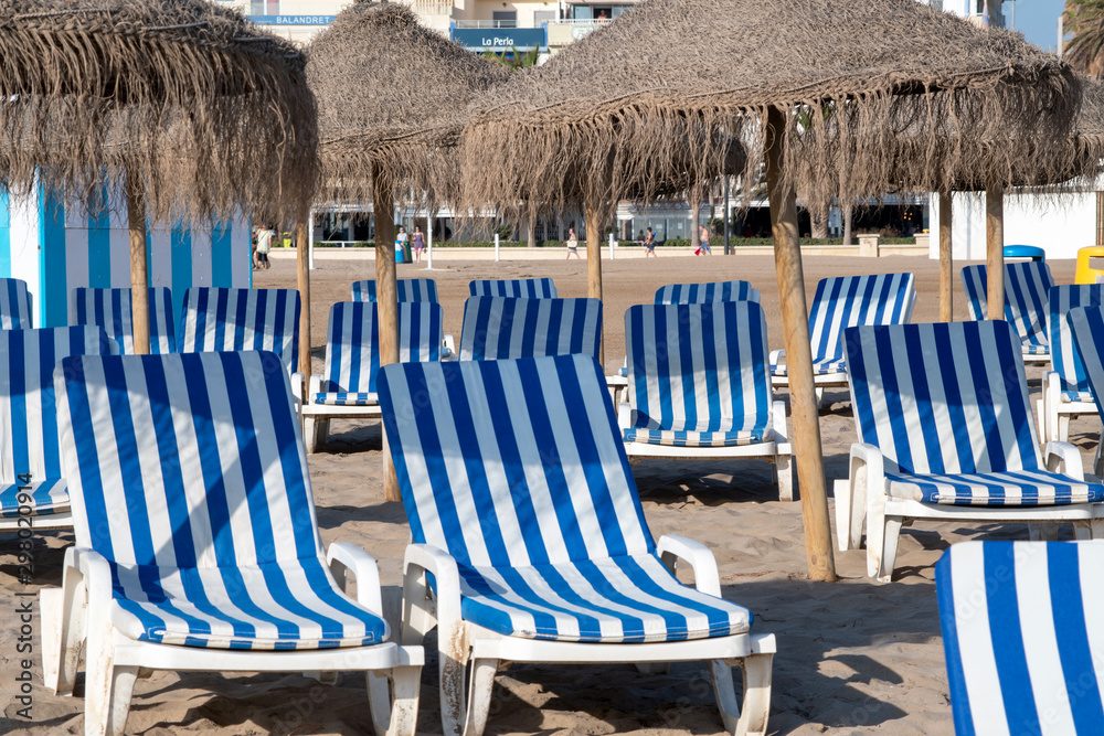 Straw umbrellas and beach loungers on Malvarrosa sand beach in Valencia