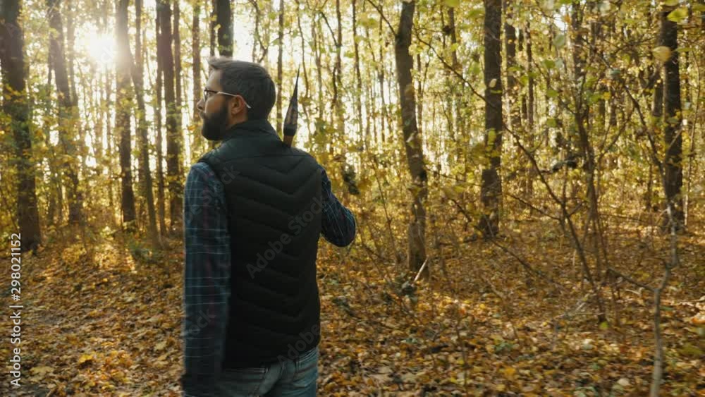 Rear view: A bearded man walks in the autumn forest with an ax on his shoulder, looking around. Slow-motion 4k video Rear view: A bearded man walks in the autumn forest with an ax on his shoulder, looking around. Slow-motion 4k video