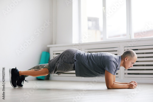 Young disabled man in sports clothing doing push-ups during sports training in the gym © AnnaStills