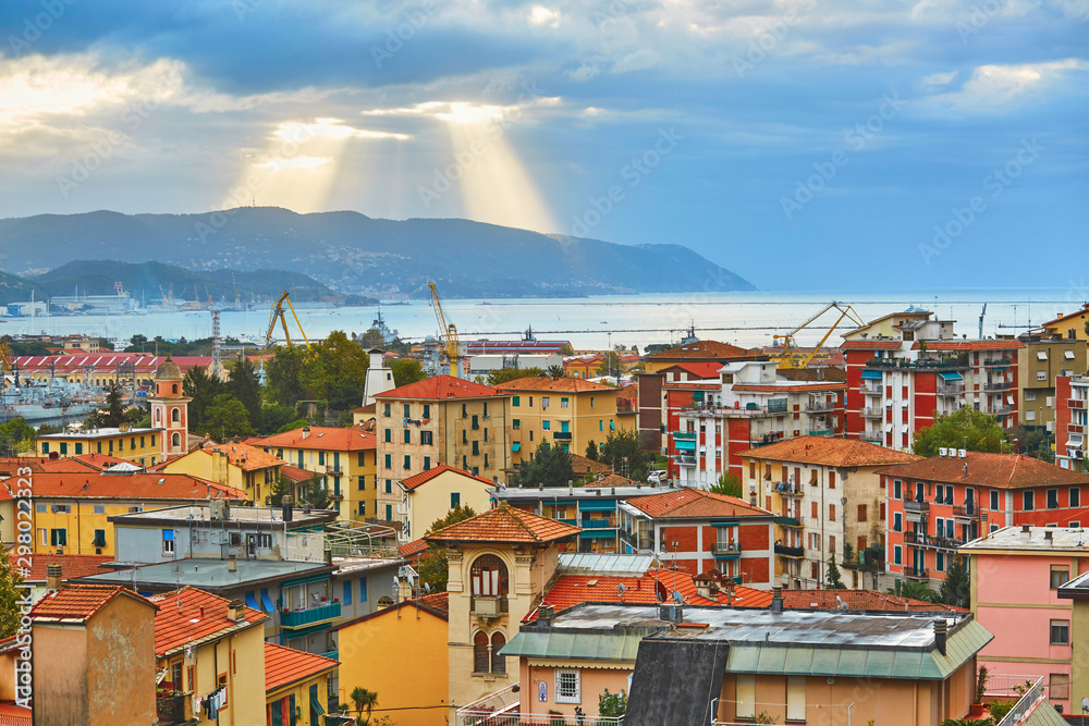 Dramatic sky with clouds and sun beams during sunrise in La Spezia