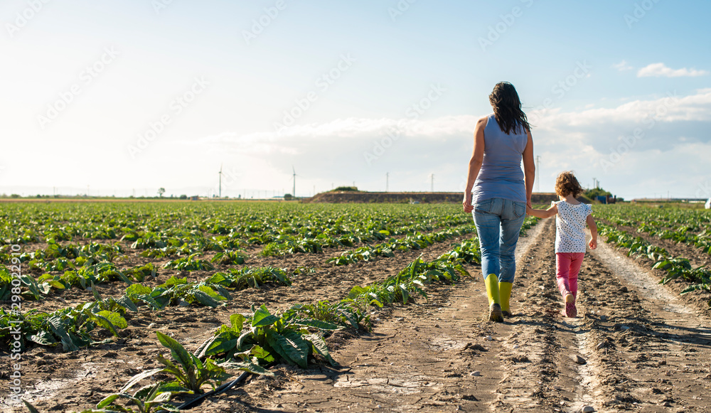 Φωτογραφία Woman farmer and little girl walking on the agriculture land.
