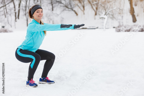 Winter workout. Girl wearing sportswear doing squats