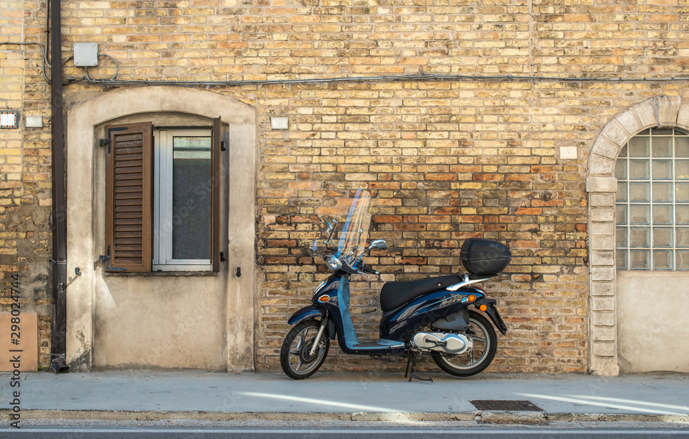 Typical italian motorbike in front of old house facade.