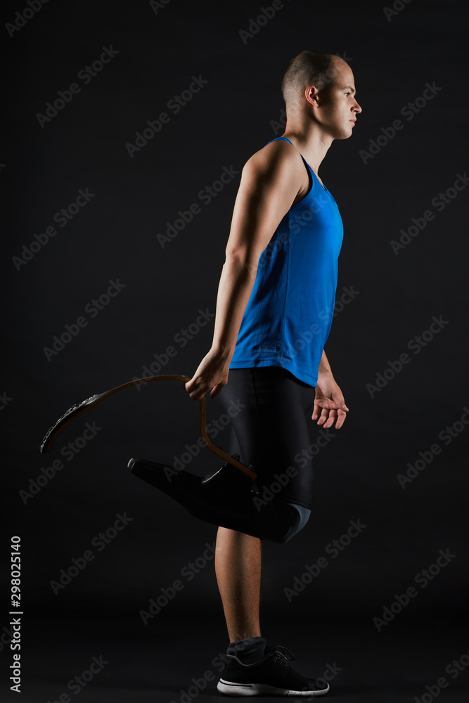 Φωτογραφία Side view of young sportsman with leg prosthesis in sports clothing standing ove