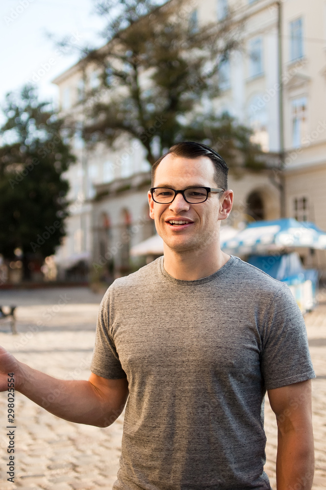 Outdoors portrait of an excited male tourist in the street with buildings of an old town in Europe in the background Outdoors portrait of an excited male tourist in the street with buildings of an old town in Europe in the background