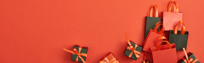 top view of gift boxes and shopping bags on red background with copy space, panoramic shot