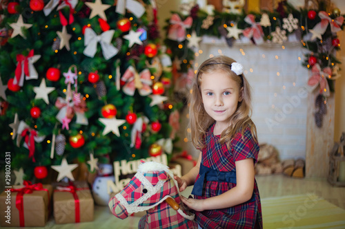 girl with a toy horse near the fireplace and Christmas tree