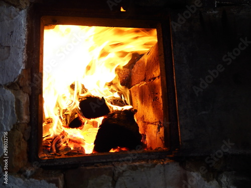 firewood burns in an old stove with a bright flame