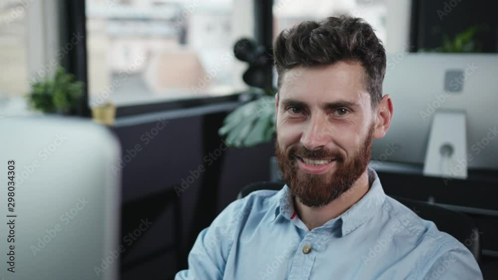 Close-up hands of employee working at modern computer. Portrait of attractive young smiling businessman in contemporary company office. Close-up hands of employee working at modern computer. Portrait of attractive young smiling businessman in contemporary company office.