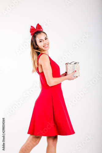 Happy excited young woman in santa claus hat with gift box over gray background
