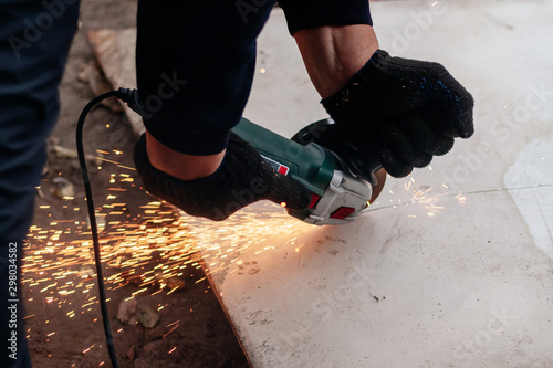 A man works with an angle grinder. Cuts metal.