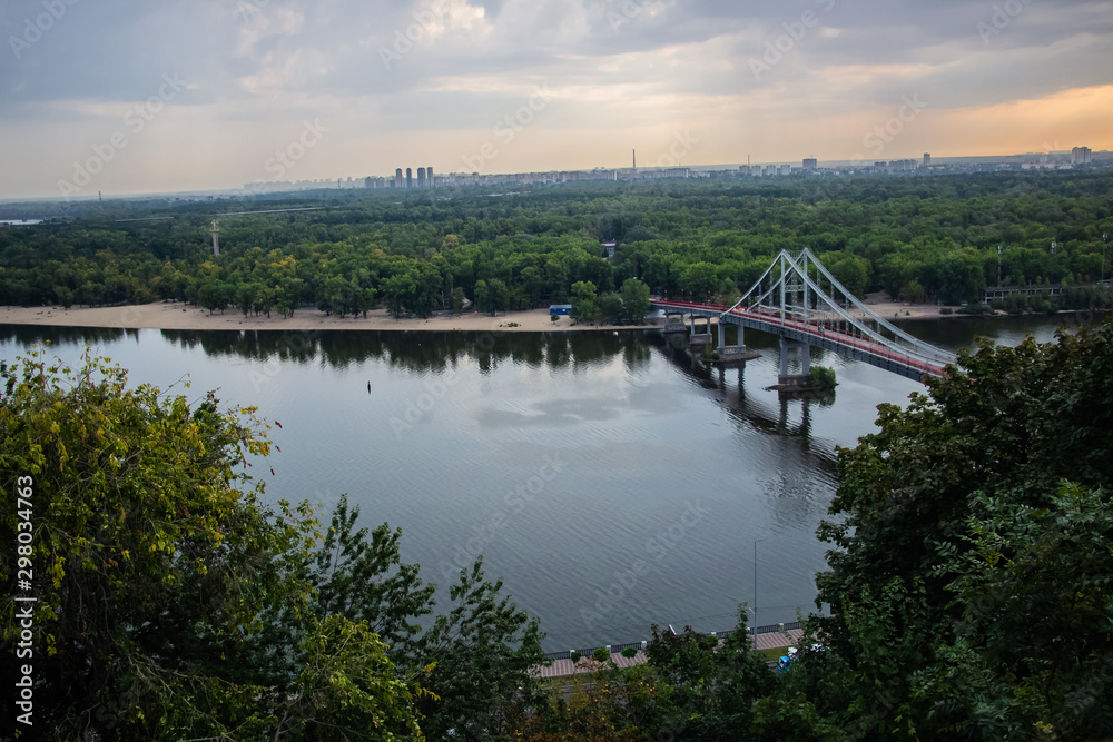 Tour of Kiev in the center of Europe. View of the Dnieper, Trukhanov island and a foot bridge. Park fountain and sunset on the horizon.. Tour of Kiev in the center of Europe. View of the Dnieper, Trukhanov island and a foot bridge. Park fountain and sunset on the horizon..