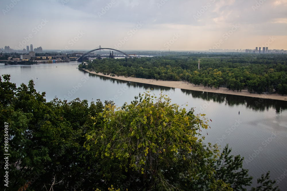 Tour of Kiev in the center of Europe. View of the Dnieper, Trukhanov island and a foot bridge. Park fountain and sunset on the horizon..