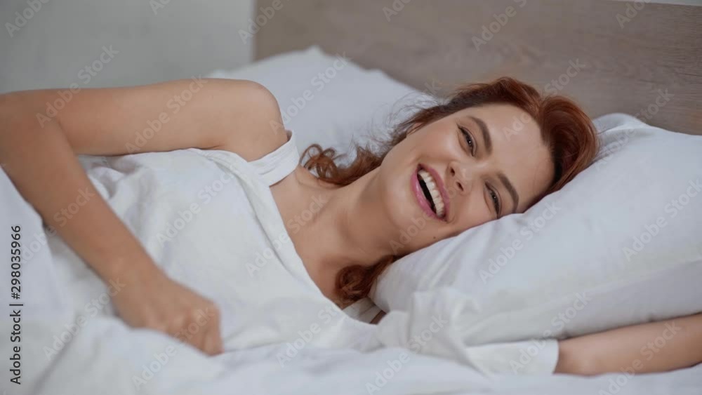 cheerful woman lying in bed and showing thumb up cheerful woman lying in bed and showing thumb up