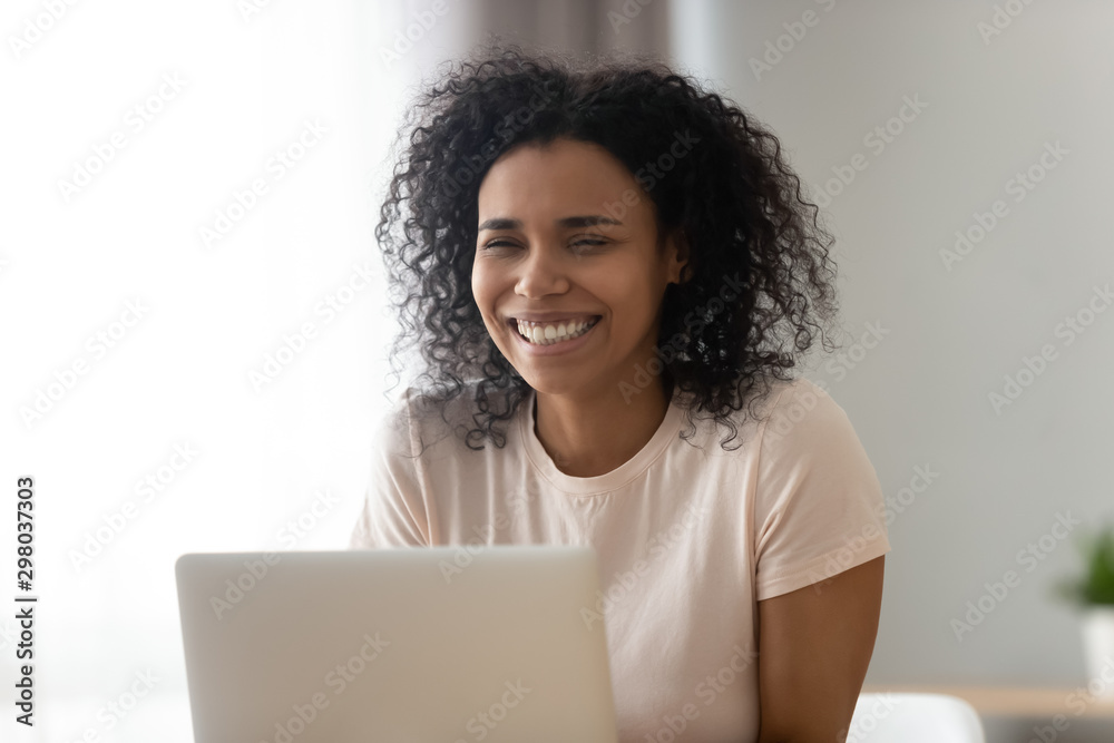 Smiling black girl laughing getting pleasant message on laptop Smiling black girl laughing getting pleasant message on laptop