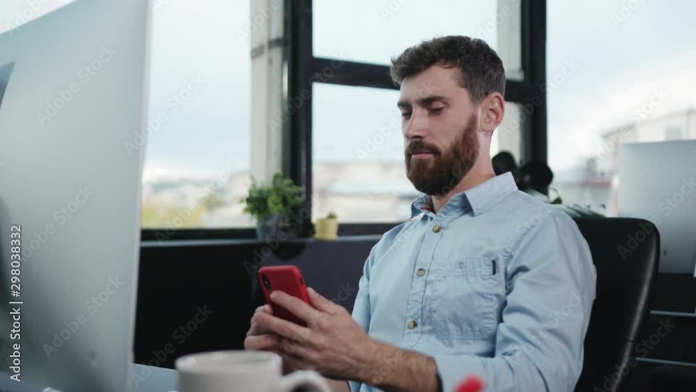 Fun handsome naughty and lazy office worker using smartphone taking selfies instead of working. Portrait of comical caucasian employee.