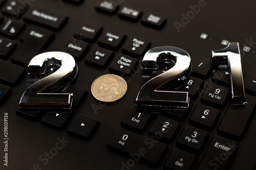 black keyboard close-up. on it are laid out numbers of metal 2021 in the center of the coin 0.25 dallar. photo