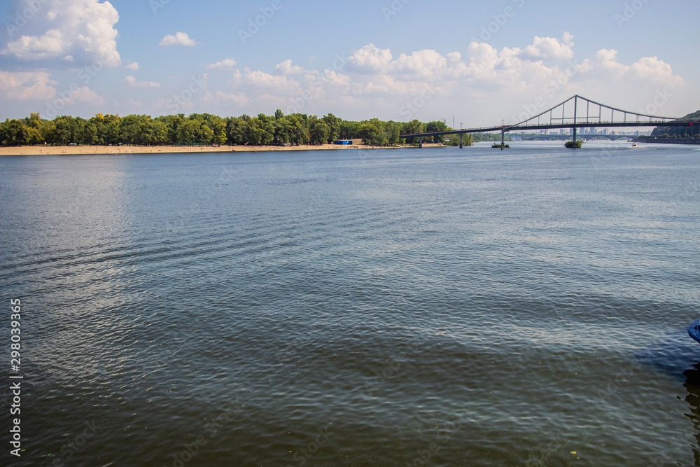 Naklejka premium Tour of Kiev in the center of Europe. View of the Dnieper, Trukhanov island and a foot bridge. Park fountain and sunset on the horizon..