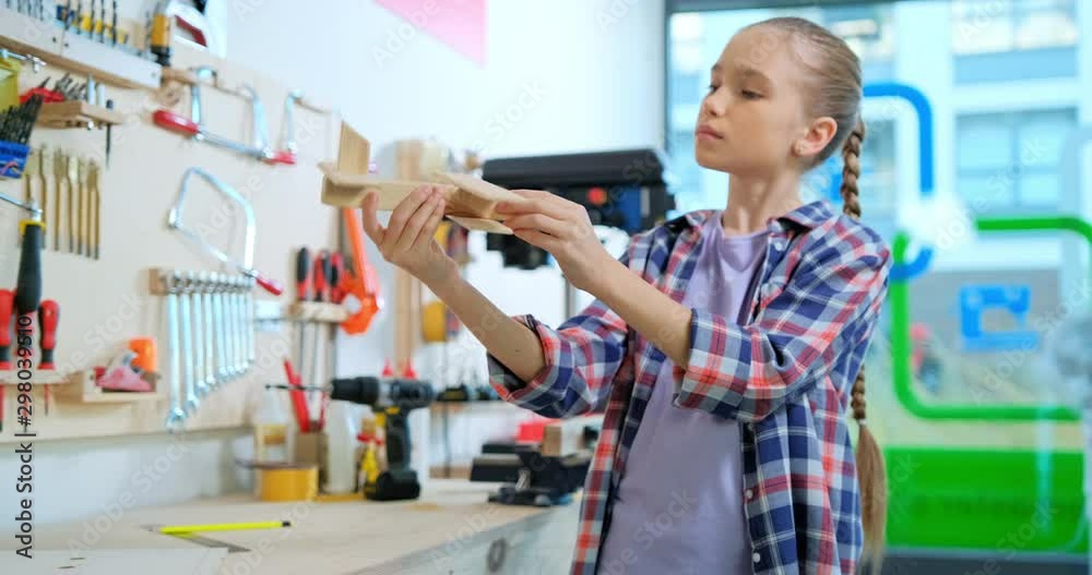 Preteen girl making aircraft model in the workshop and smiling at camera Stock Video | Adobe Stock