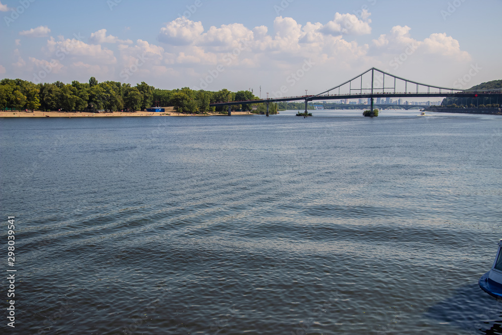 Naklejka premium Tour of Kiev in the center of Europe. View of the Dnieper, Trukhanov island and a foot bridge. Park fountain and sunset on the horizon..