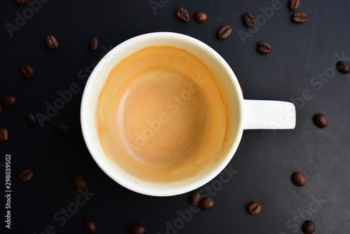 The empty cap of Coffee on the of dark wood table have many coffee beans. photo