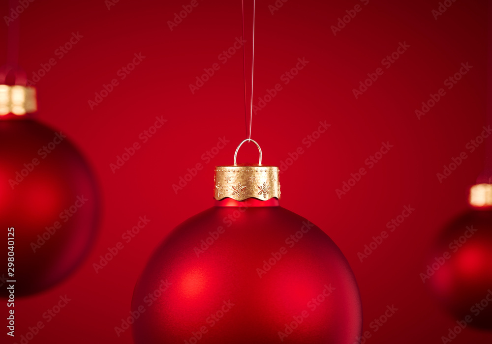Christmas baubles hanging in front of red background.