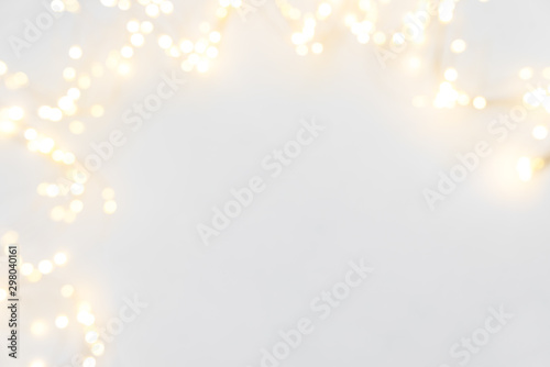 Border of defocused Christmas lights on white wooden background. Christmas and New Year holidays celebration concept photo