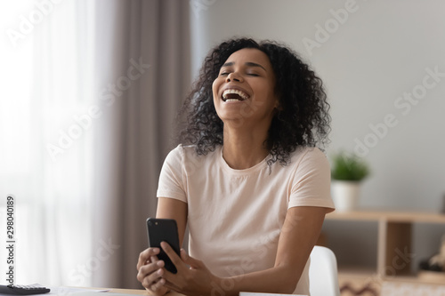 Smiling black girl laughing watching funny video on cellphone