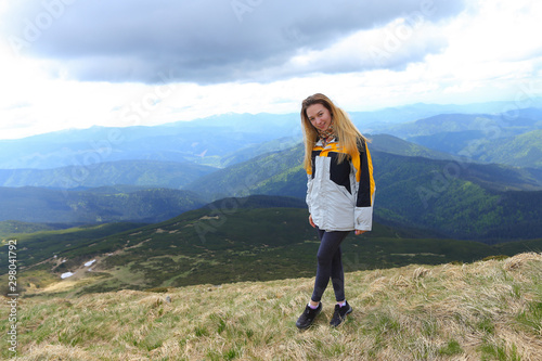 Young female tourist wearing yellow jacket standing in Alps mountains. photo